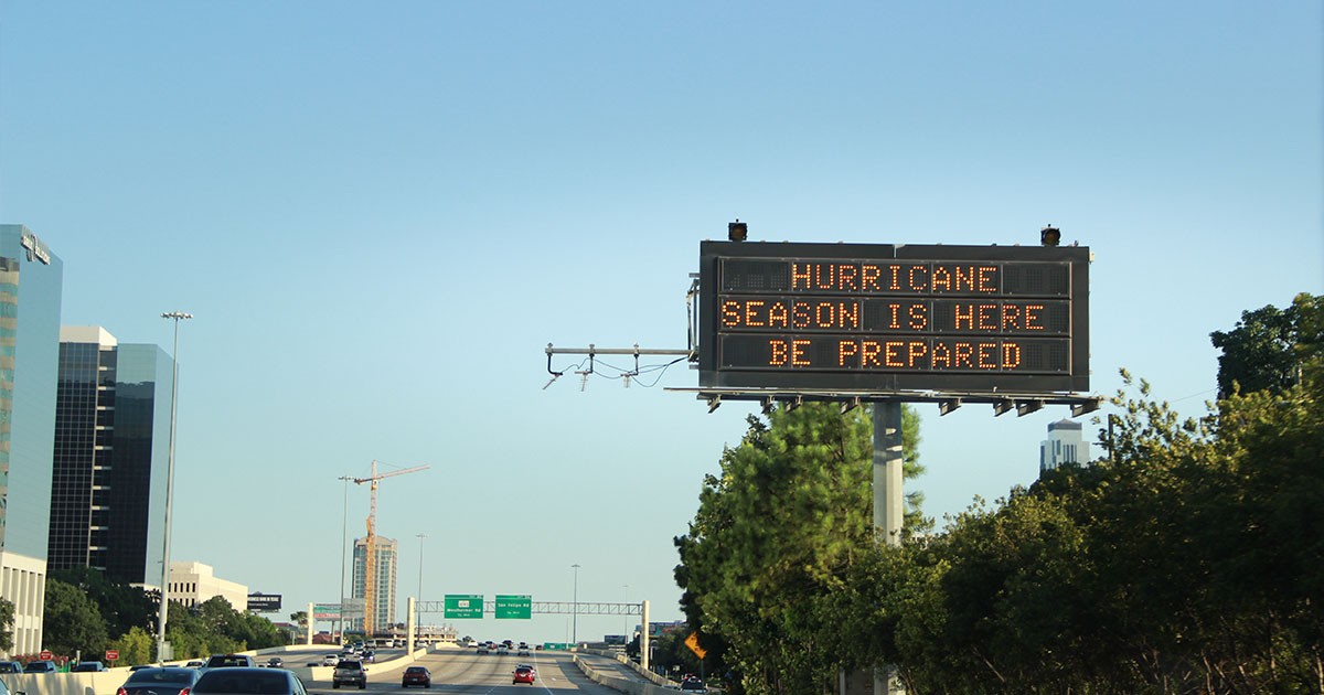 Highway scene with an electronic billboard displaying 'Hurricane Season is Here, Be Prepared.'