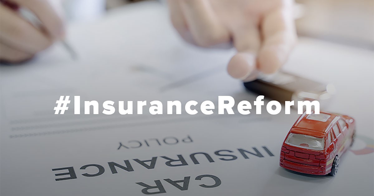 A toy car on a car insurance policy document with the hashtag "#InsuranceReform."