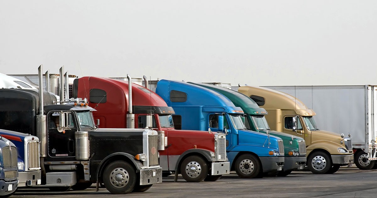 A row of colorful semi-trucks parked at a lot.